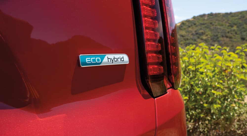 A close up of the hybrid badge on a red 2022 Kia Sorento Hybrid is shown.