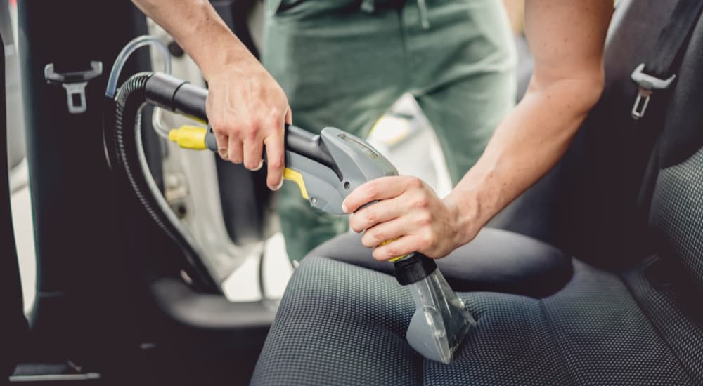 A person is shown vacuuming a vehicle.