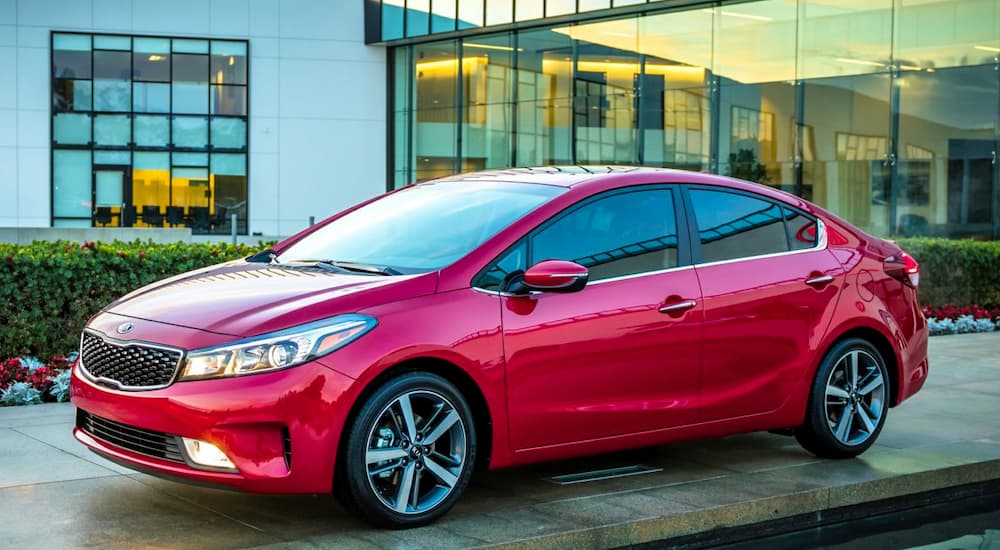 A red 2017 Kia Forte is shown from the front at an angle while parked in front of a house.