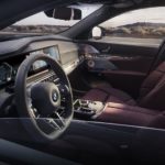The red interior of a 2022 BMW 7-series shows the steering wheel and infotainment screen.