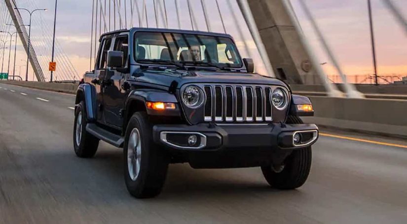 A grey 2022 Jeep Wrangler is shown from the front while crossing a bridge during a 2022 Jeep Wrangler vs 2022 Jeep Gladiator comparison.
