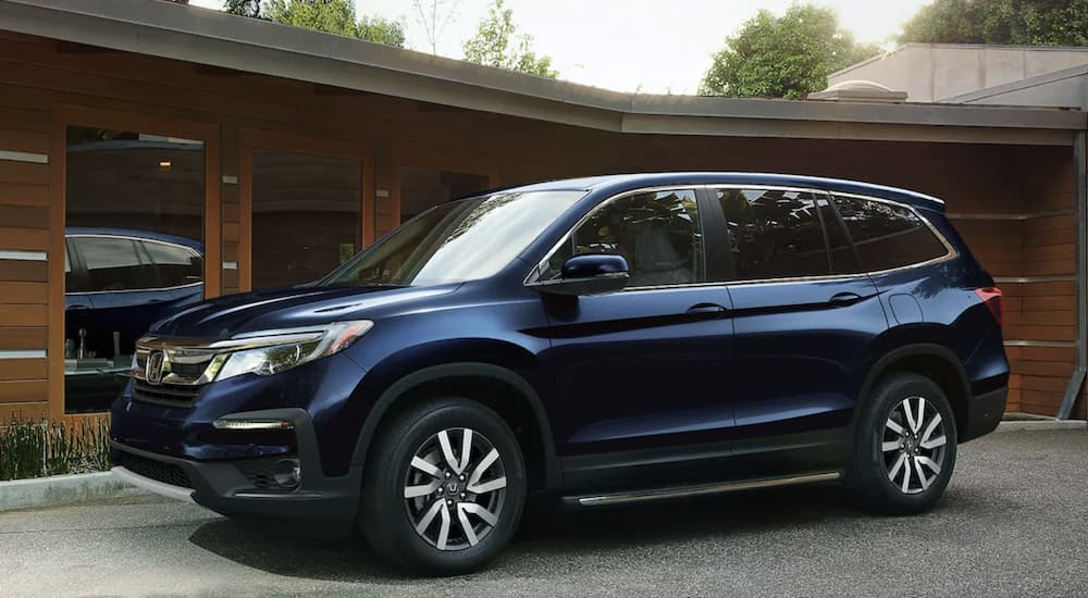 A blue 2022 Honda Pilot EX-L is shown parked in front of a modern house.