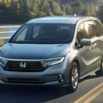 A silver 2023 Honda Odyssey Elite is shown driving on an open road.