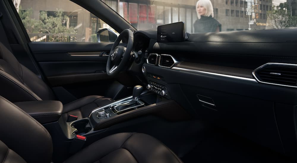 The black interior of a 2023 Mazda CX-5 shows the steering wheel.