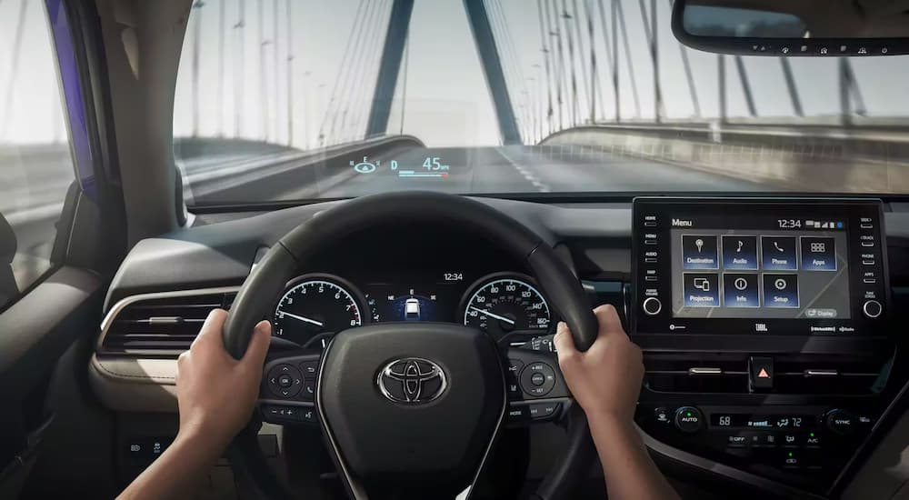 A driver is shown driving on a bridge in a 2023 Toyota Camry.