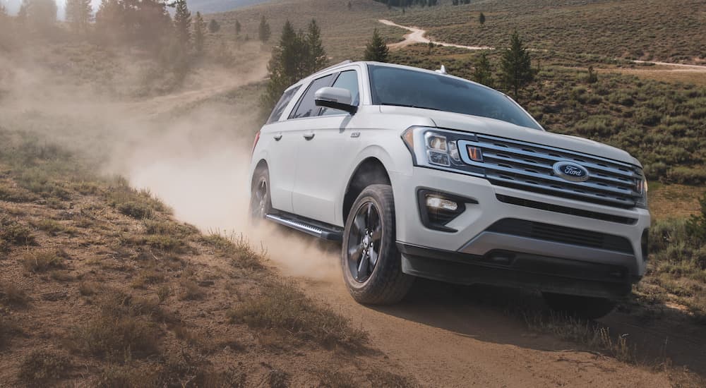 A white 2023 Ford Expedition is shown from the front while it drives up a dirt hill.