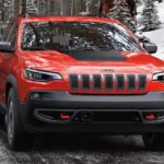 A red 2021 Jeep Cherokee Latitude LUX is shown driving on a snowy road.