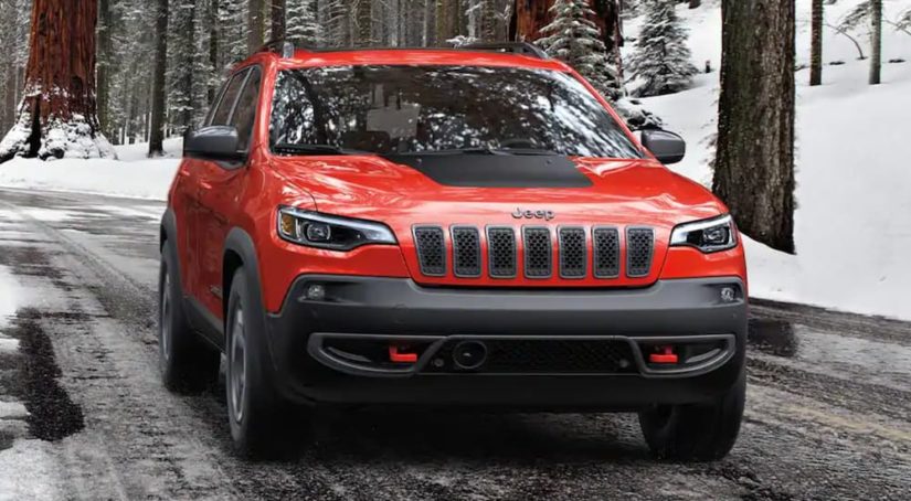 A red 2021 Jeep Cherokee Latitude LUX is shown driving on a snowy road.
