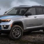 A grey 2022 Jeep Grand Cherokee 4xe is shown from the side parked in a forest.