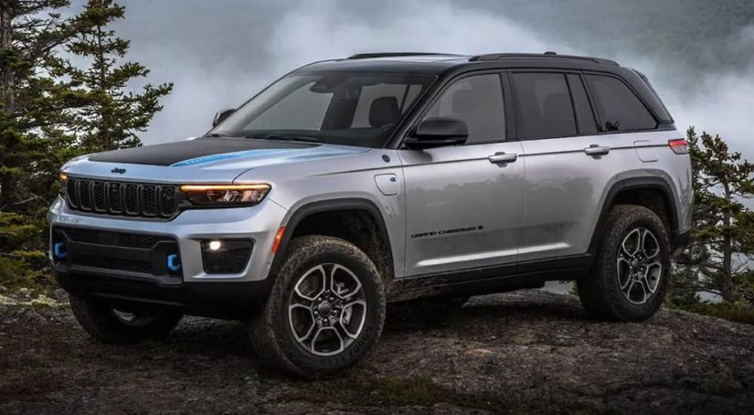 A grey 2022 Jeep Grand Cherokee 4xe is shown from the side parked in a forest.