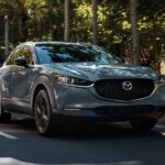 A grey 2022 Mazda CX-30 is shown driving on a suburban street.