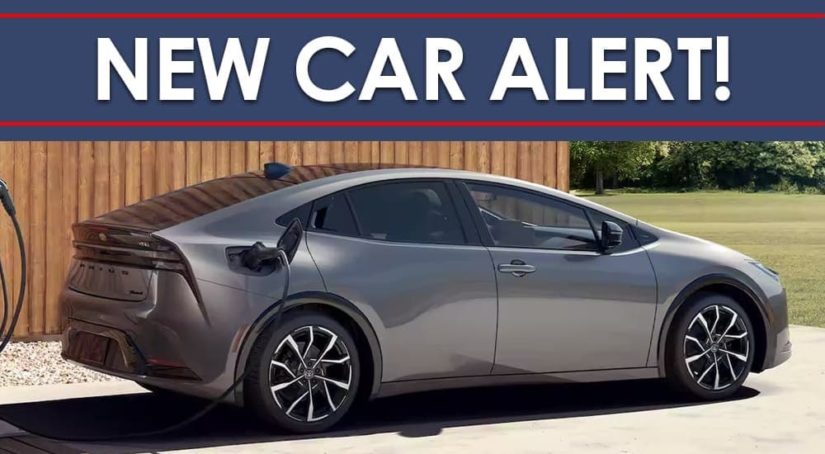 A silver 2023 Toyota Prius Prime XSE Premium is shown charging in a driveway below a new car alert banner.