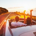 A couple is shown driving a vintage car.
