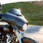A man is shown riding a black 2022 Harley-Davidson Street Glide on an open highway.