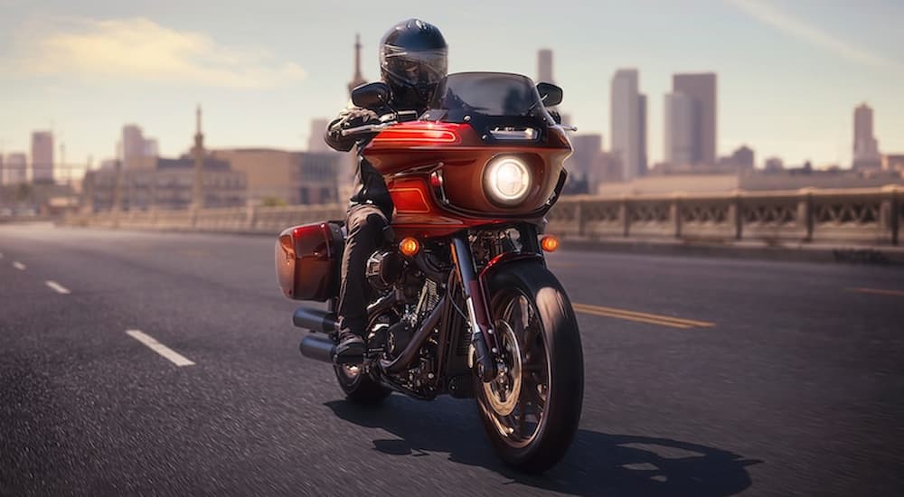 A red 2022 Harley-Davidson Low Rider El Diablo is shown driving on a city highway.