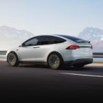 A white 2022 Tesla Model X is shown driving on an open highway.