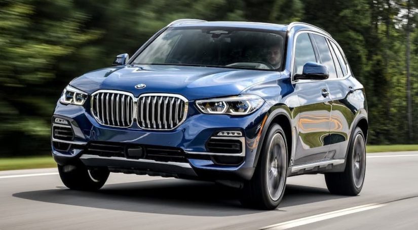 A blue 2018 BMW X5 is shown from the front driving on an open road.