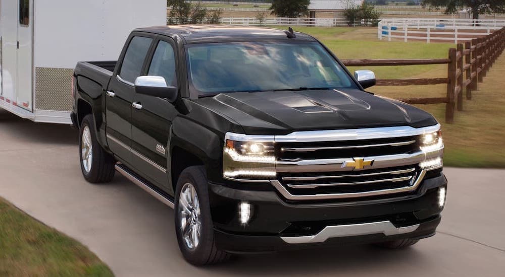 A black 2018 Chevy Silverado 1500 High Country is shown towing a trailer.