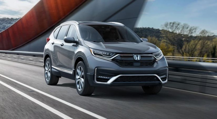 A used Honda CR-V for sale, a grey 2020 Honda CR-V, is shown driving on an open road.
