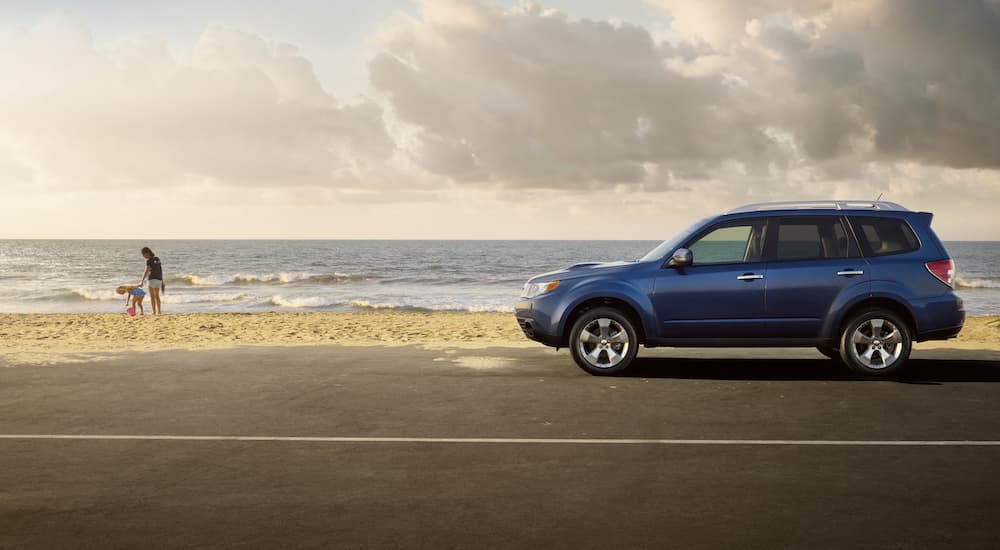 A blue 2010 Subaru Forester is shown from the side parked at the beach.