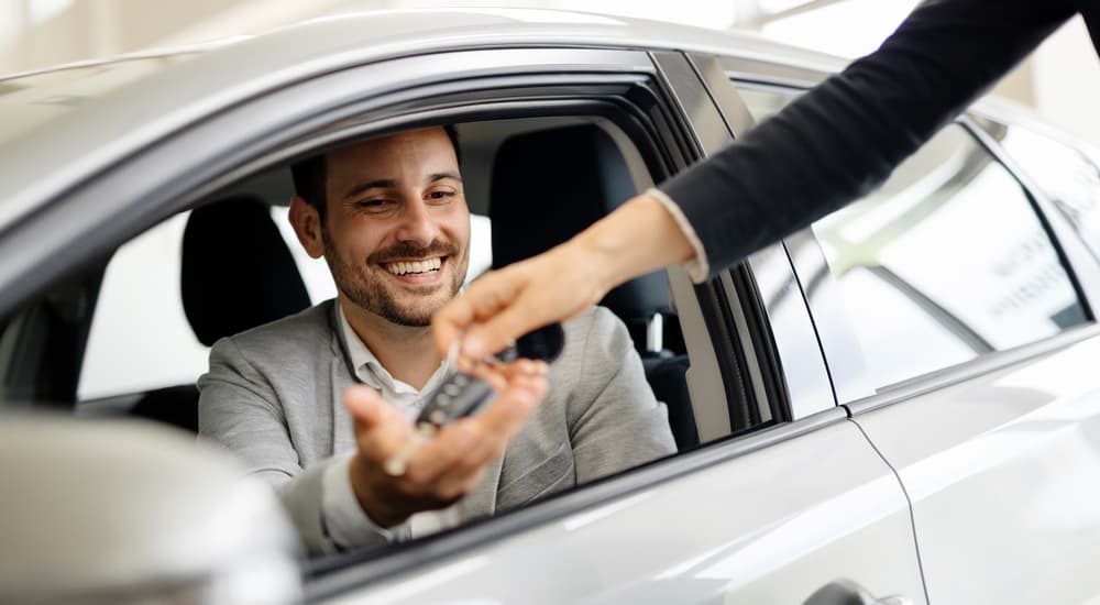 A car salesman is shown handing a key to customer.
