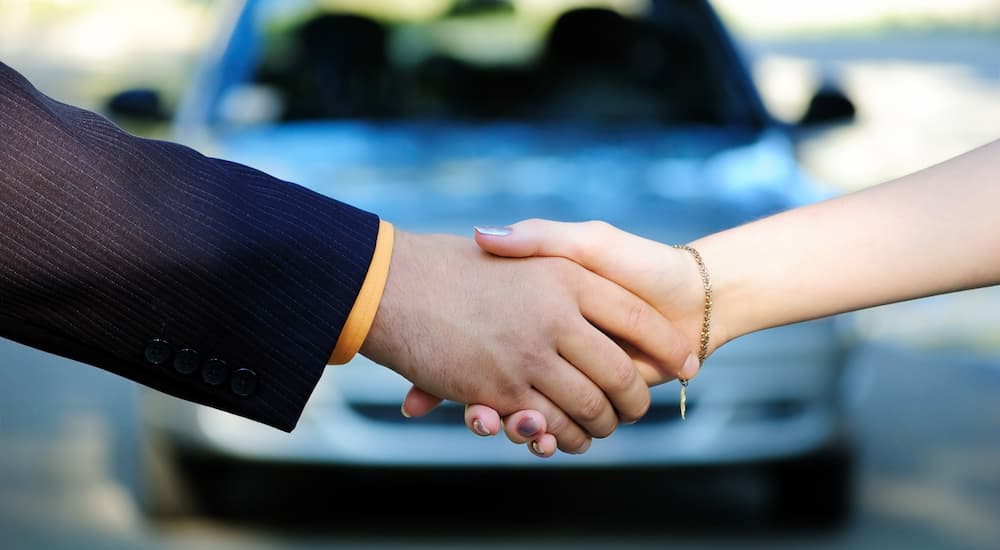 A customer and car salesman are shown shaking hands after talking about VW leasing.