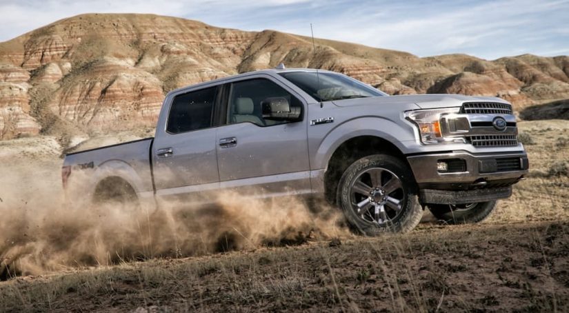A grey 2020 Ford F-150 is shown from the side driving through a desert.