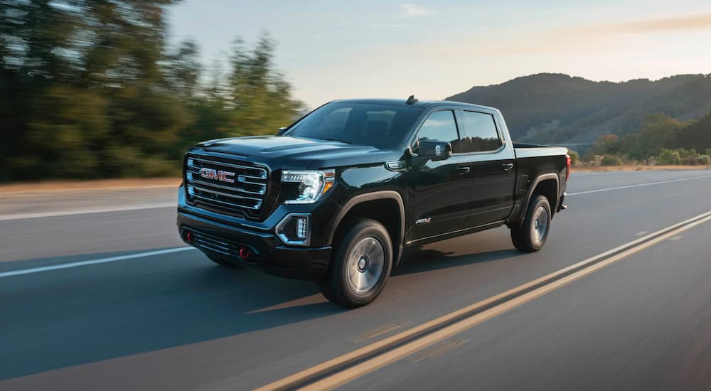 A black 2020 GMC Sierra 1500 AT4 is shown driving on an open road.