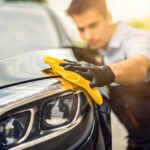 A man is shown cleaning a car with a yellow rag.