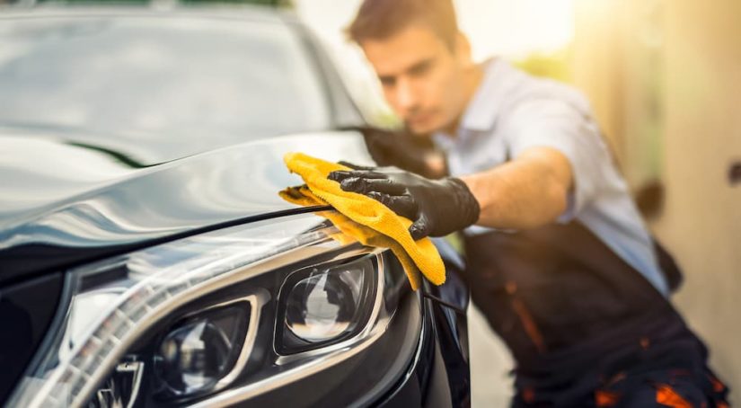 A man is shown cleaning a car with a yellow rag.