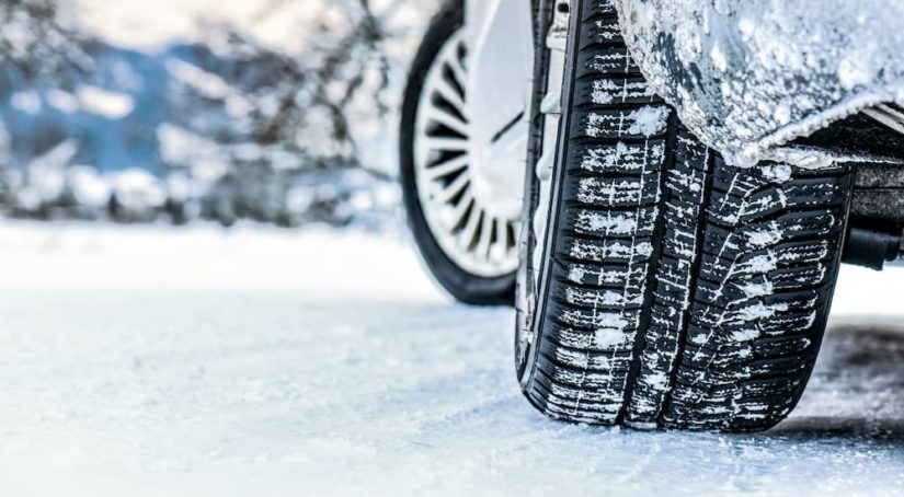A snowy car is shown from a low angle after searching 'winter tires near me.'