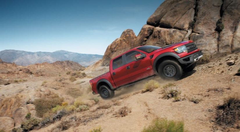 A red 2014 Ford F-150 Raptor is shown from the side after leaving a certified Ford truck dealer.