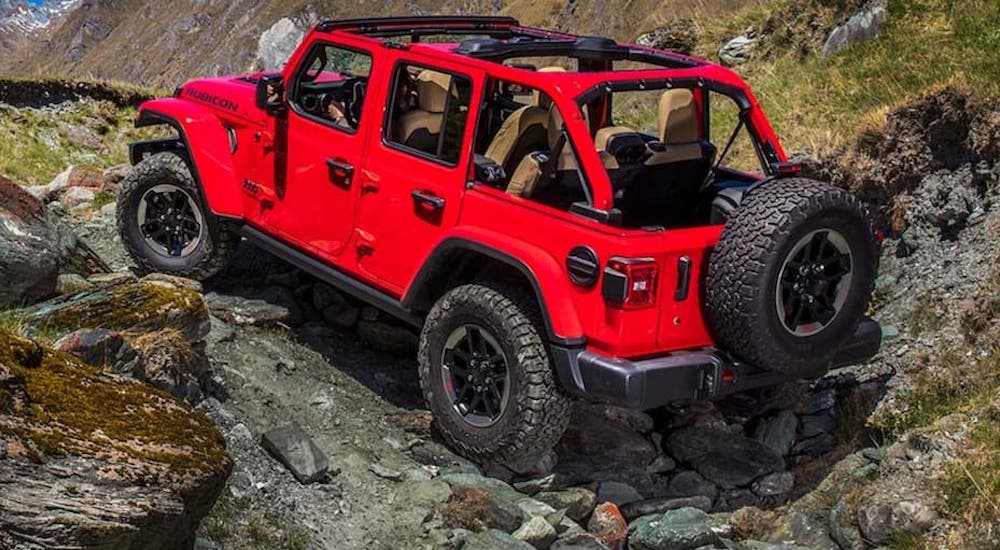 A red 2020 Jeep Wrangler Unlimited is shown from the rear in a rocky area.