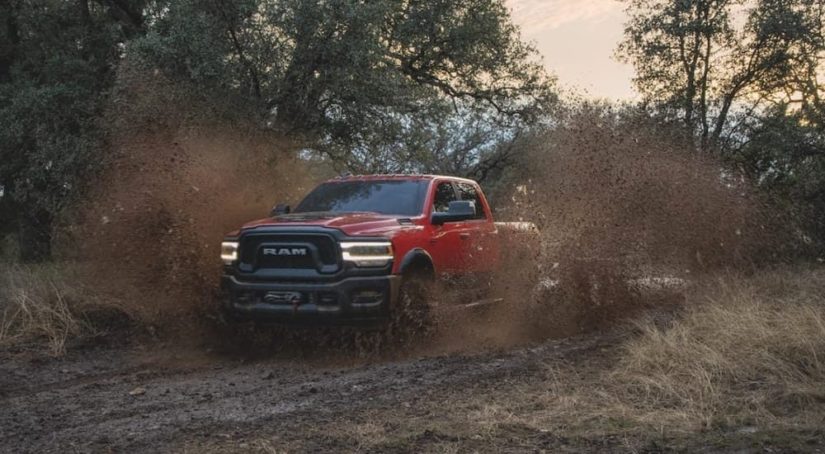 A red 2020 Ram 2500 Power Wagon is shown from the front while it drives through mud after leaving a Certified Pre-Owned Ram dealer.