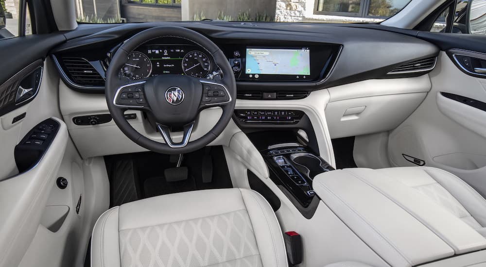 The white interior of a 2023 Buick Envision Avenir is shown from the driver's seat.