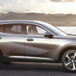 A silver 2023 Buick Envision is shown from the side on a lakeshore.
