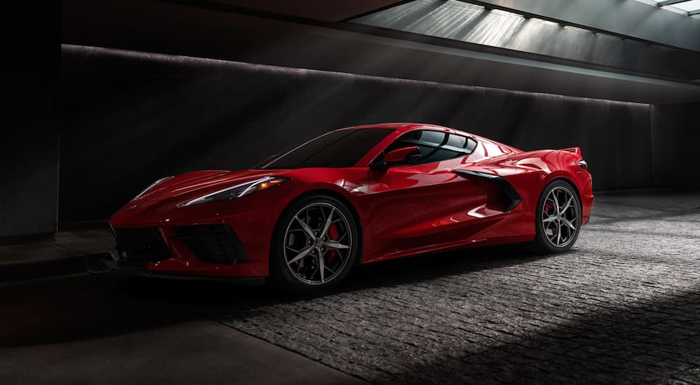 A red 2021 Chevy Corvette is shown from the side in a dark warehouse.