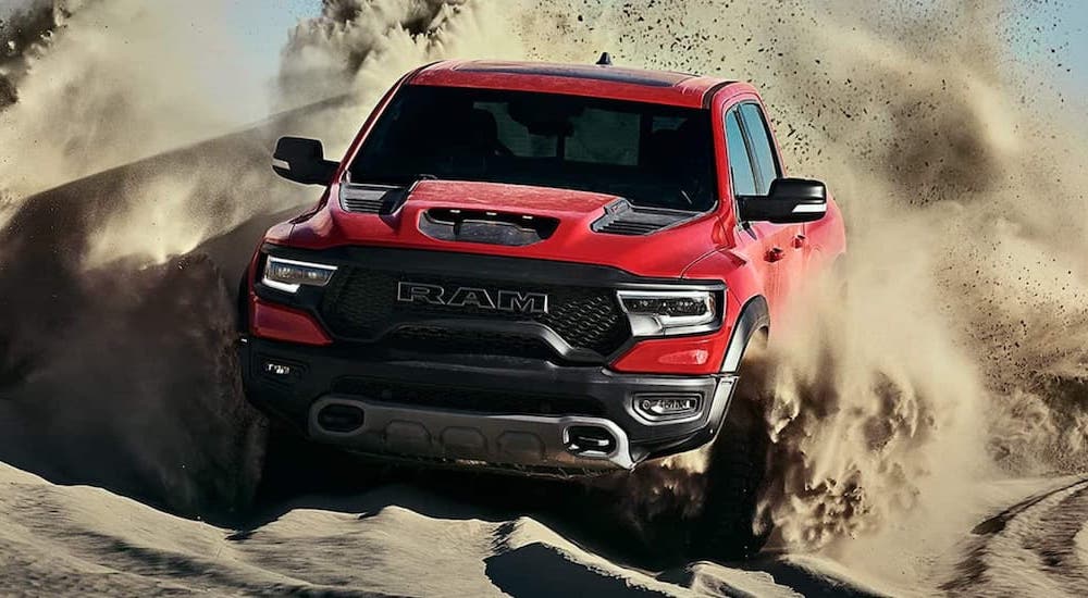 A red 2021 Ram 1500 TRX is shown from the front while driving through sand.