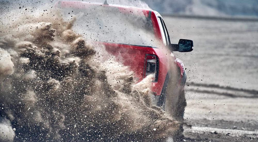 A red 2023 Ram 1500 TRX is shown from the rear while it kicks up sand.