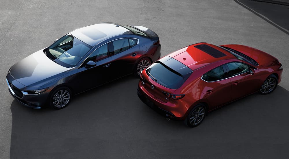 A grey and a red 2022 Mazda3 are shown from a high angle parked on pavement.