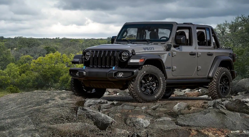 A grey 2023 Jeep Willys is shown from the front at an angle on a rocky area.