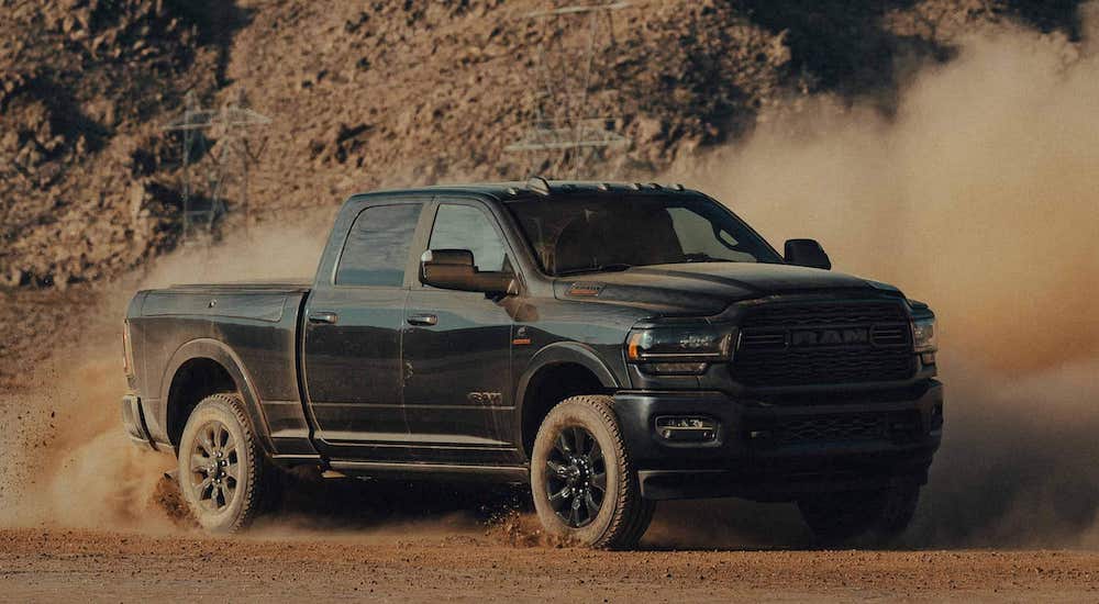 A black 2022 Ram 2500 Cummins is shown from the front at an angle while kicking up dust.