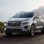 A grey 2023 Chevy Equinox is shown driving on an open road during a 2023 Chevy Equinox vs 2023 Honda CR-V comparison.