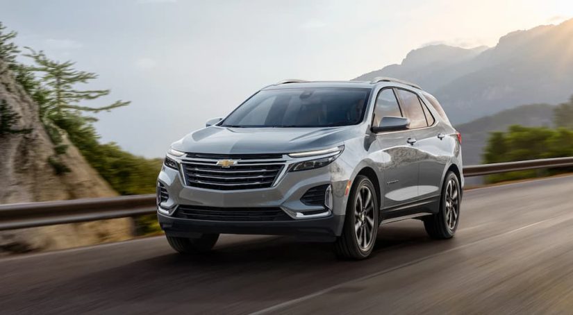 A grey 2023 Chevy Equinox is shown driving on an open road during a 2023 Chevy Equinox vs 2023 Honda CR-V comparison.