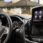 The black interior of a 2023 Chevy Traverse shows the steering wheel and infotainment screen.