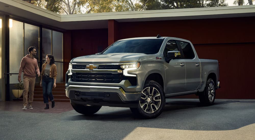 A grey 2023 Chevy Silverado 1500 is shown parked in front of a house.