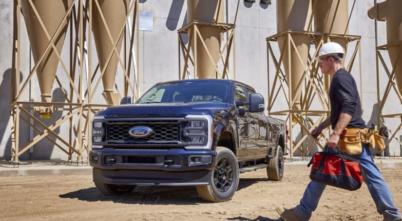 A blue 2023 Ford F-250 STX is shown parked at a construction site.