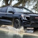 A black 2023 GMC Terrain is shown from the front driving through a puddle.