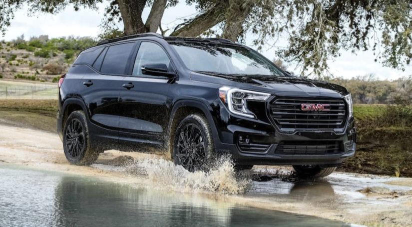 A black 2023 GMC Terrain is shown from the front driving through a puddle.