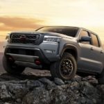 A grey 2023 Nissan Frontier is shown parked on a rock.